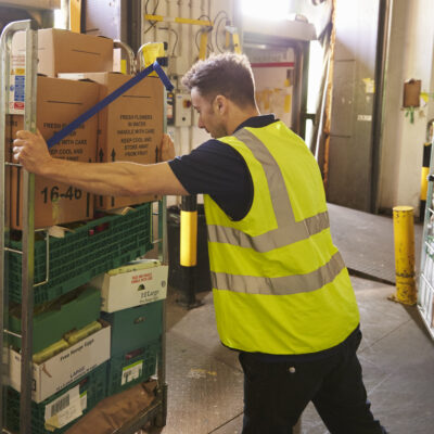 Man pushing a roll cage ready for delivery in a warehouse