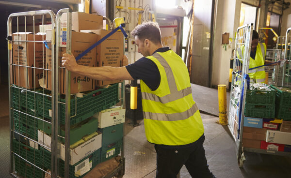 Man pushing a roll cage ready for delivery in a warehouse